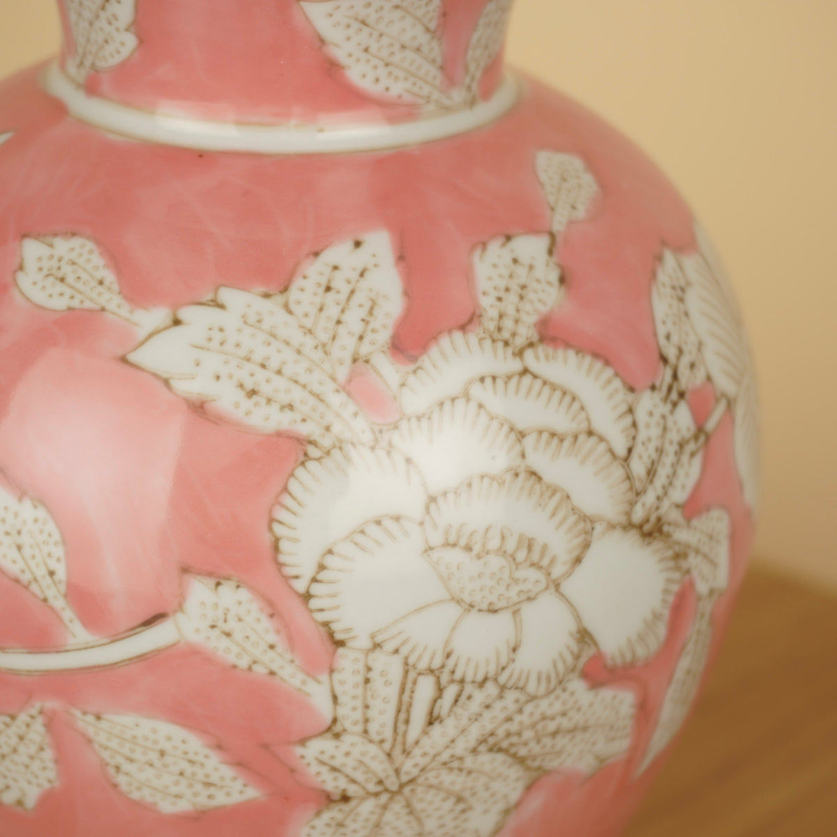 Detail van witte bloemen en bladeren met fijne bruine lijnen op het glanzende roze oppervlak van de vaas.
