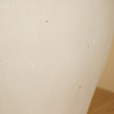 Detail van het matte oppervlak van een crèmekleurige vaas met fijne structuur en kleine donkere spikkels.