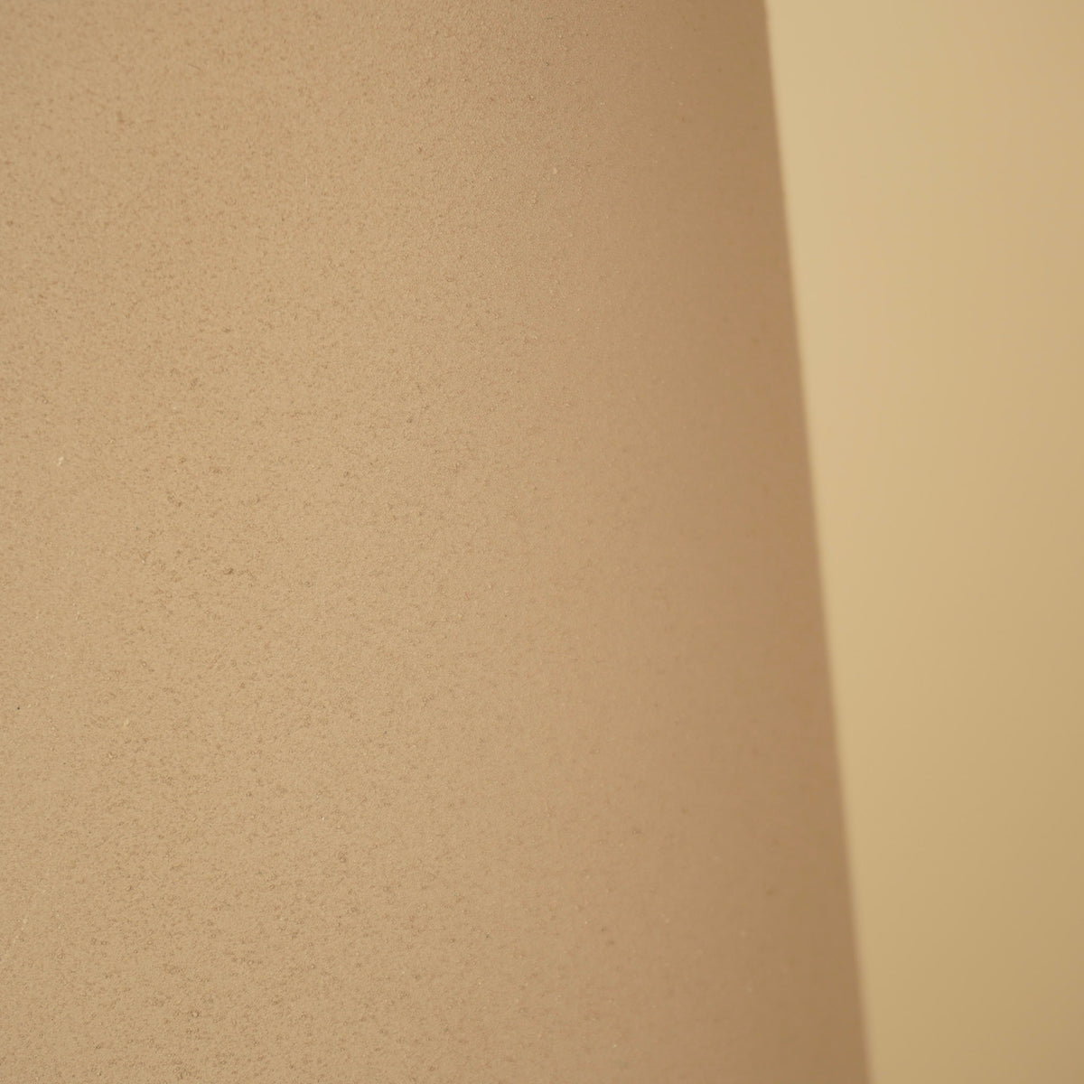 Detail van het matte, zandkleurige oppervlak van de vaas met een fijne korrelstructuur.