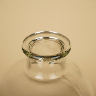 Detail van de smalle ronde opening met dikke, afgeronde glazen rand van een transparante flesvaas.