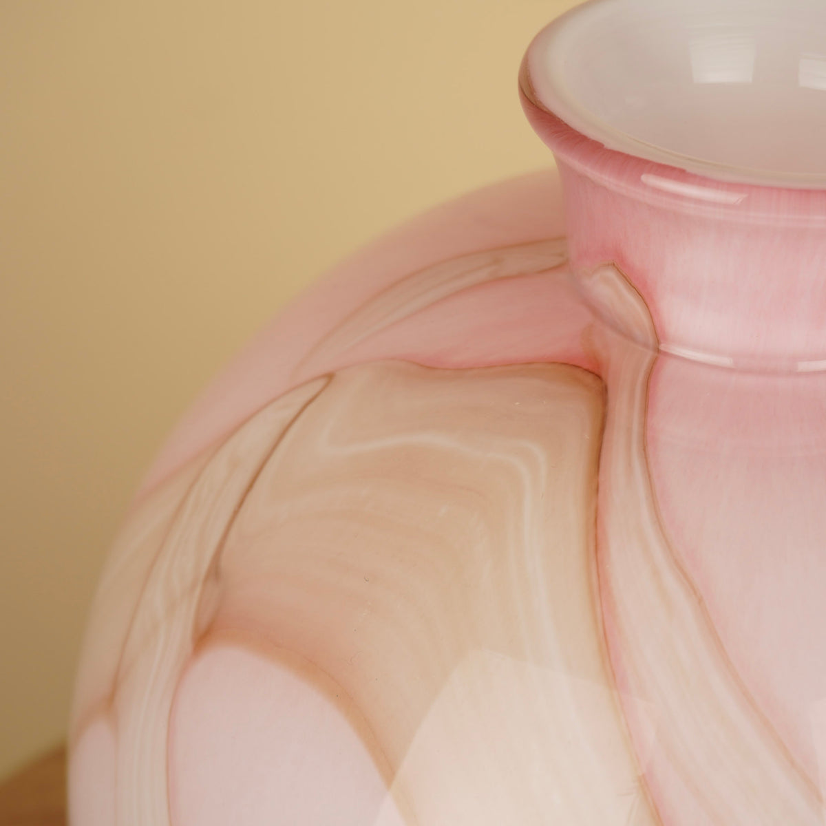Detail van het golvende marmerpatroon in roze, crème en beige op de glanzende vaas.